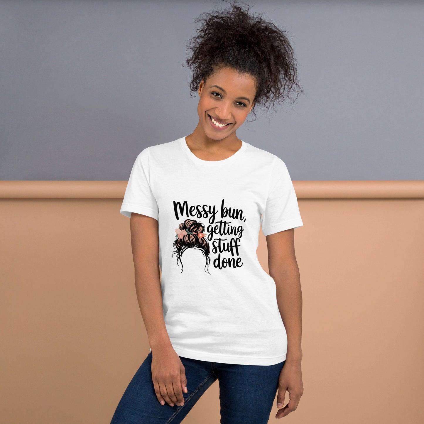 Smiling woman wearing a white t-shirt with black text that says 'Messy Bun, Getting Stuff Done' and a messy bun illustration