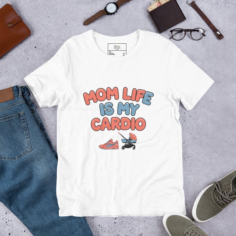 White unisex t-shirt laid flat on a surface next to jeans and accessories, featuring the phrase 'Mom Life Is My Cardio' in pastel letters with sneakers and pacifier graphic.