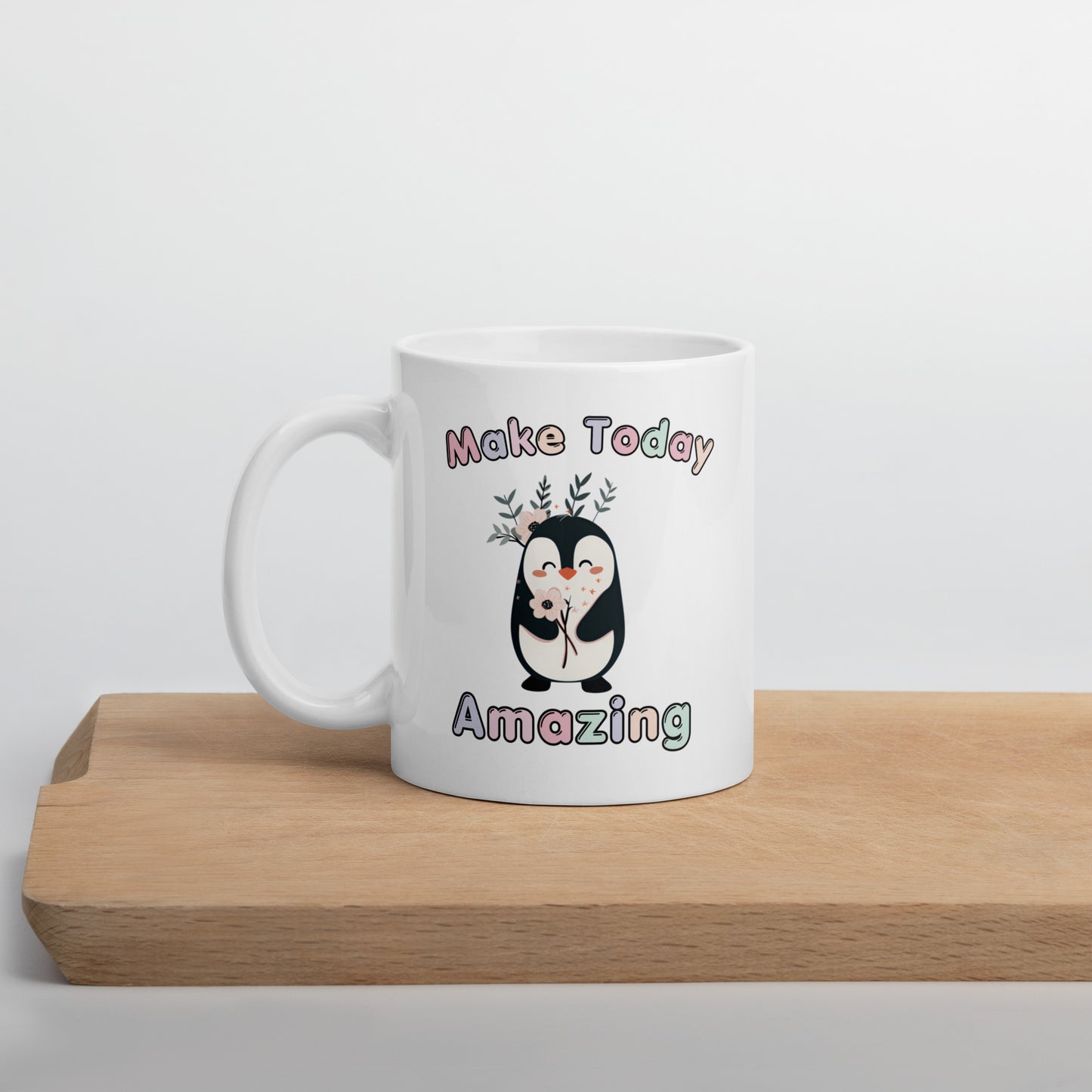 White ceramic mug on office desk with the text 'Make Today Amazing' and a cute penguin illustration