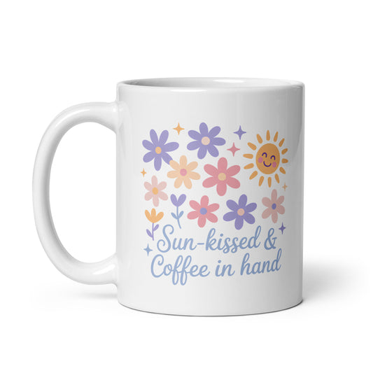White ceramic mug with pastel flowers, smiling sun, and “Sun-kissed & Coffee in Hand” text – handle on the left side – summer coffee mug for moms by Happily Styled