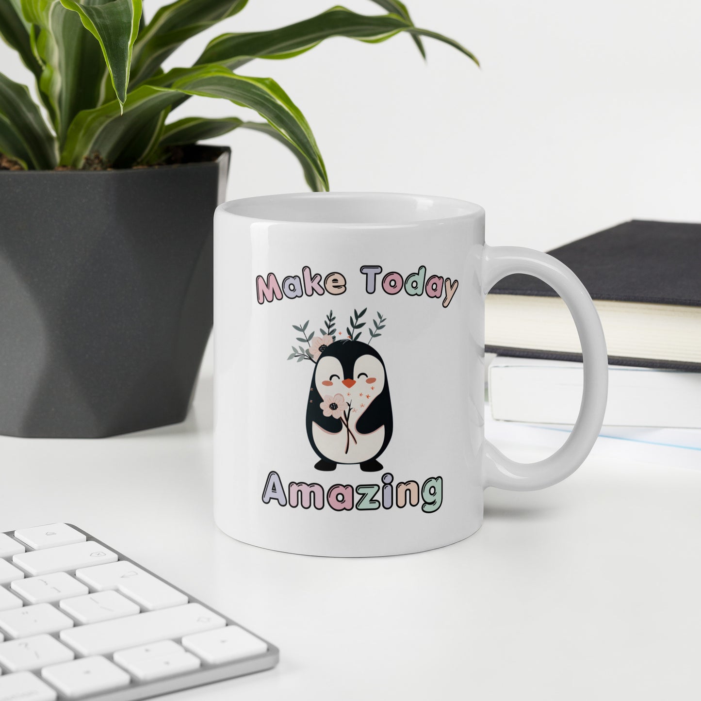 White ceramic mug on office desk with the text 'Make Today Amazing' and a cute penguin illustration