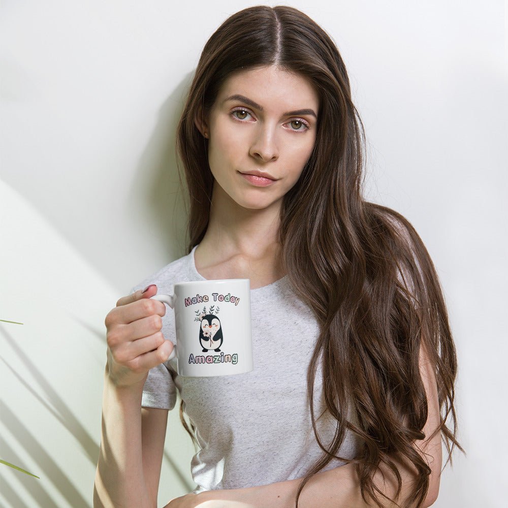 Young woman with long brown hair holding a white mug that says 'Make Today Amazing' with cute penguin illustration