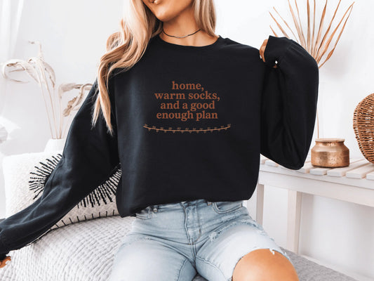Person wearing a black sweatshirt with text, sitting on a couch in a cozy living room.