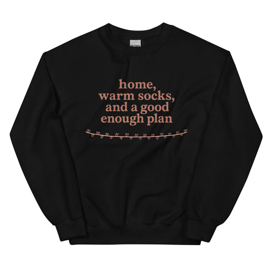 Black sweatshirt with text 'home, warm socks, and a good enough plan' on a white background