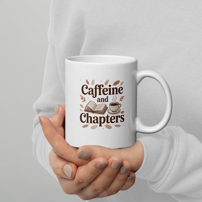 White mug with 'Caffeine and Chapters' text held by a person against a gray background