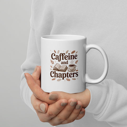 White mug with 'Caffeine and Chapters' text held by a person against a gray background