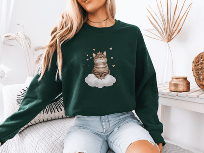 Woman wearing a forest green sweatshirt featuring a majestic tabby cat sitting on a fluffy cloud, surrounded by soft pink hearts 