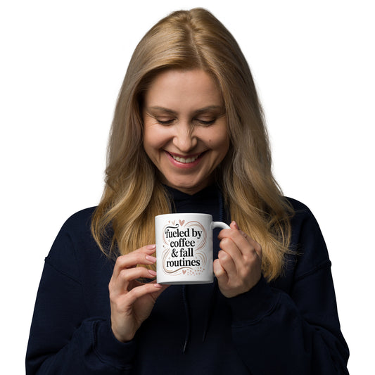 Woman holding a mug with text "fueled by coffee and fall routines" on a white background