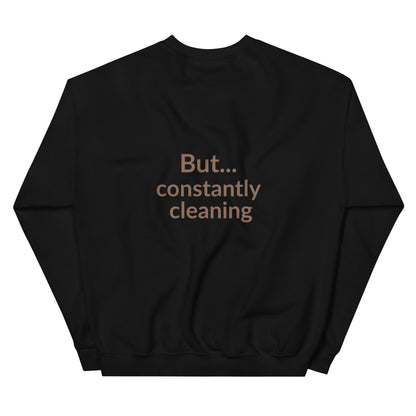 Black sweatshirt with text 'But... constantly cleaning' on a white background