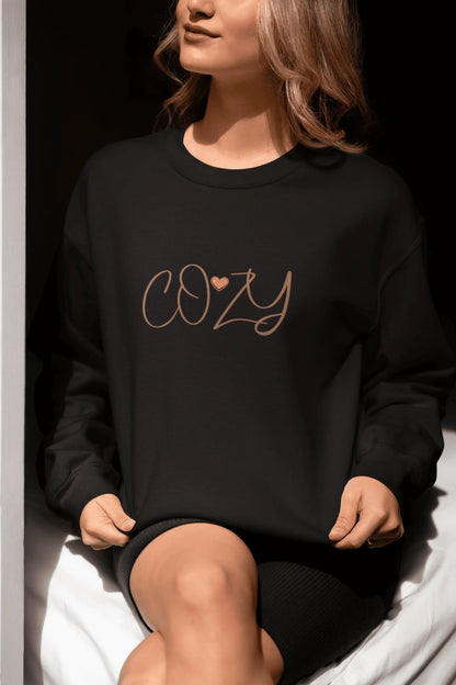Person wearing a black sweatshirt with 'COZY' text sitting on a white surface.