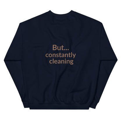 Navy blue sweatshirt with text 'But... constantly cleaning' on a white background