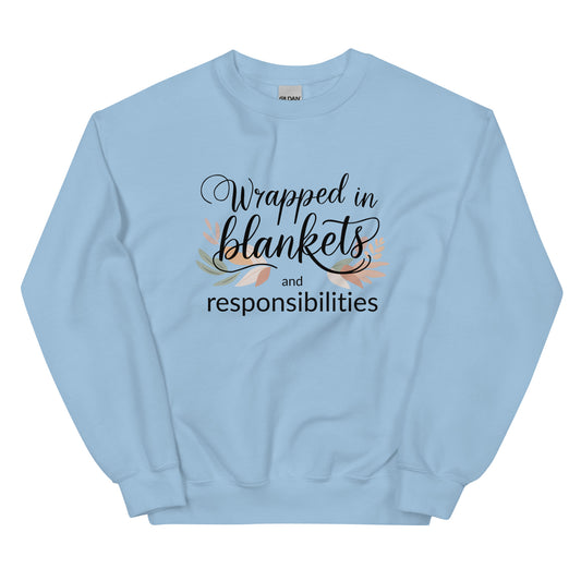 Light blue sweatshirt with text 'Wrapped in blankets and responsibilities' on a white background