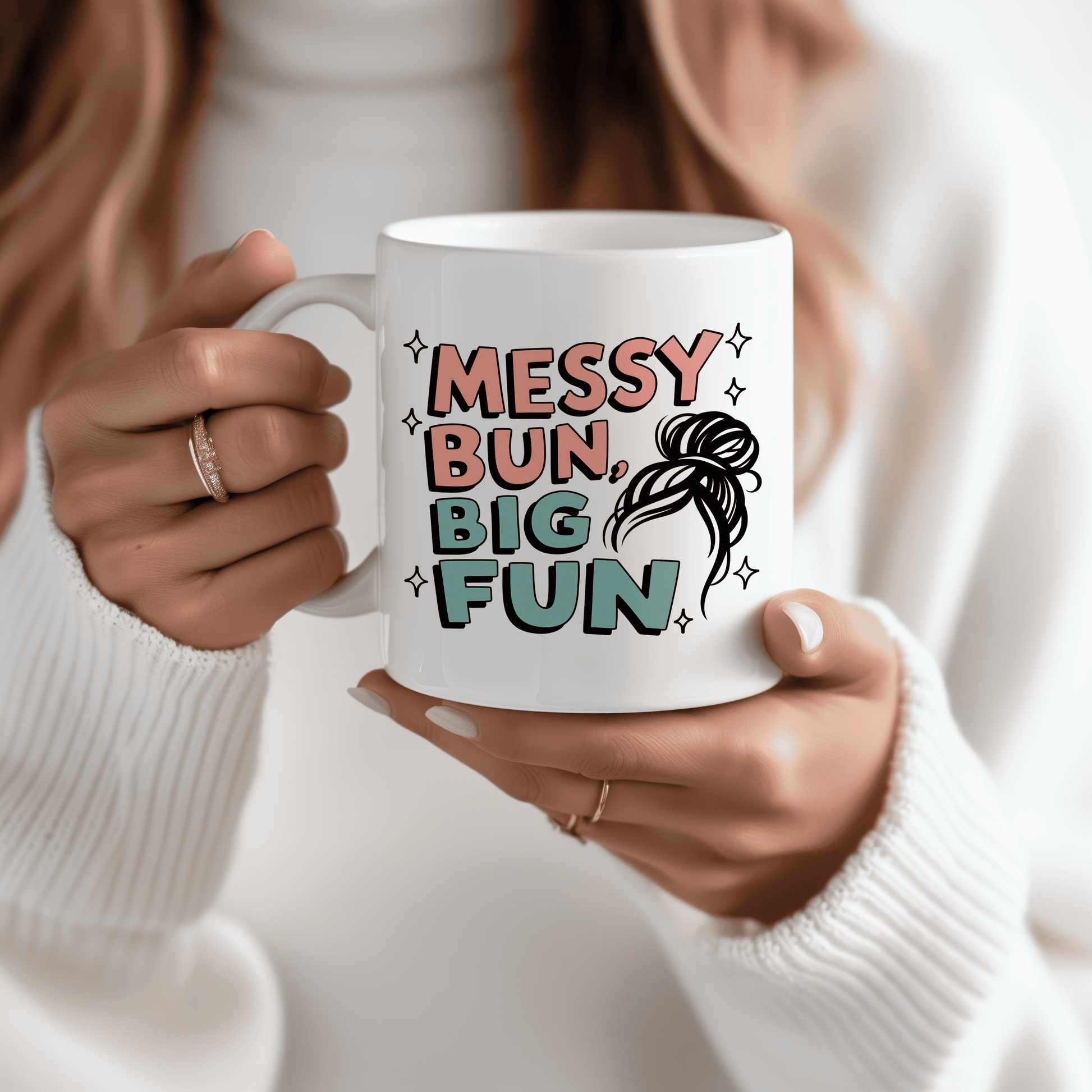 Woman holding white ceramic mug with pastel lettering that says “Messy Bun, Big Fun” and a fun sketch of a messy hairstyle