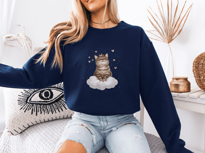 Woman wearing a navy blue sweatshirt featuring a majestic tabby cat sitting on a fluffy cloud, surrounded by soft pink hearts 