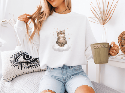 Woman holding a green coffee mug and wearing a white sweatshirt featuring a regal tabby cat sitting on a cloud