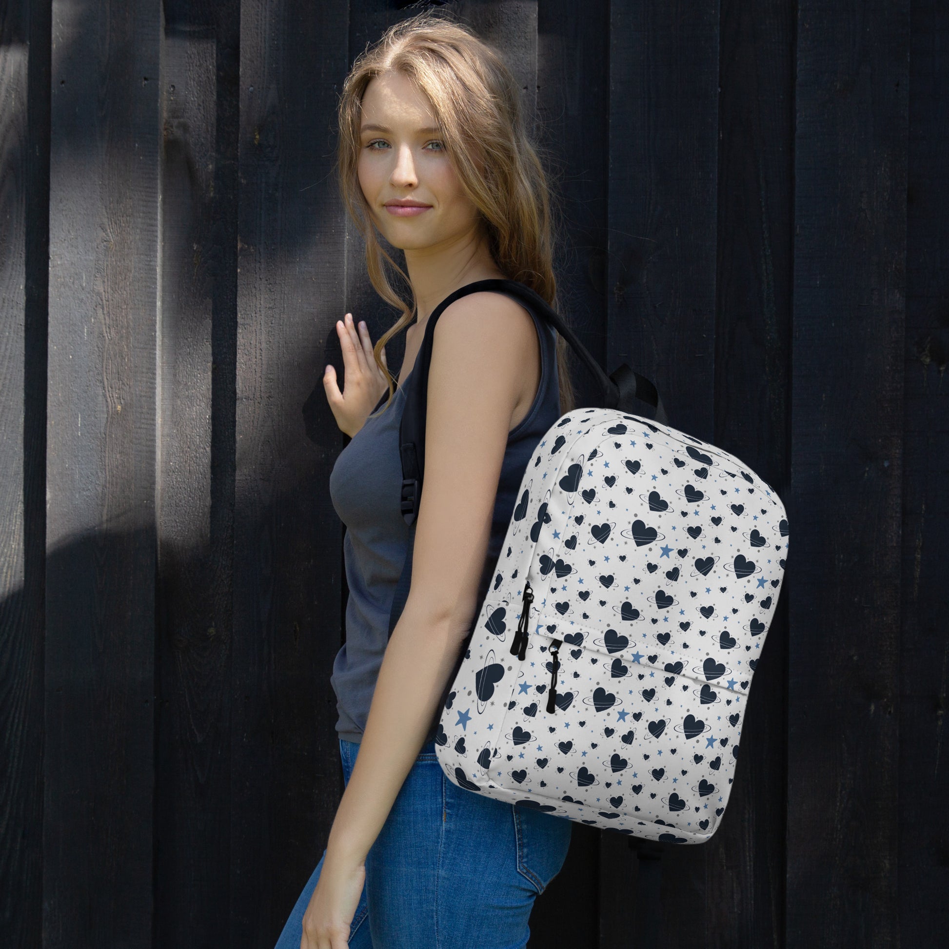 Woman wearing white backpack with all-over navy heart and star pattern, front pocket and visible inside pocket label 