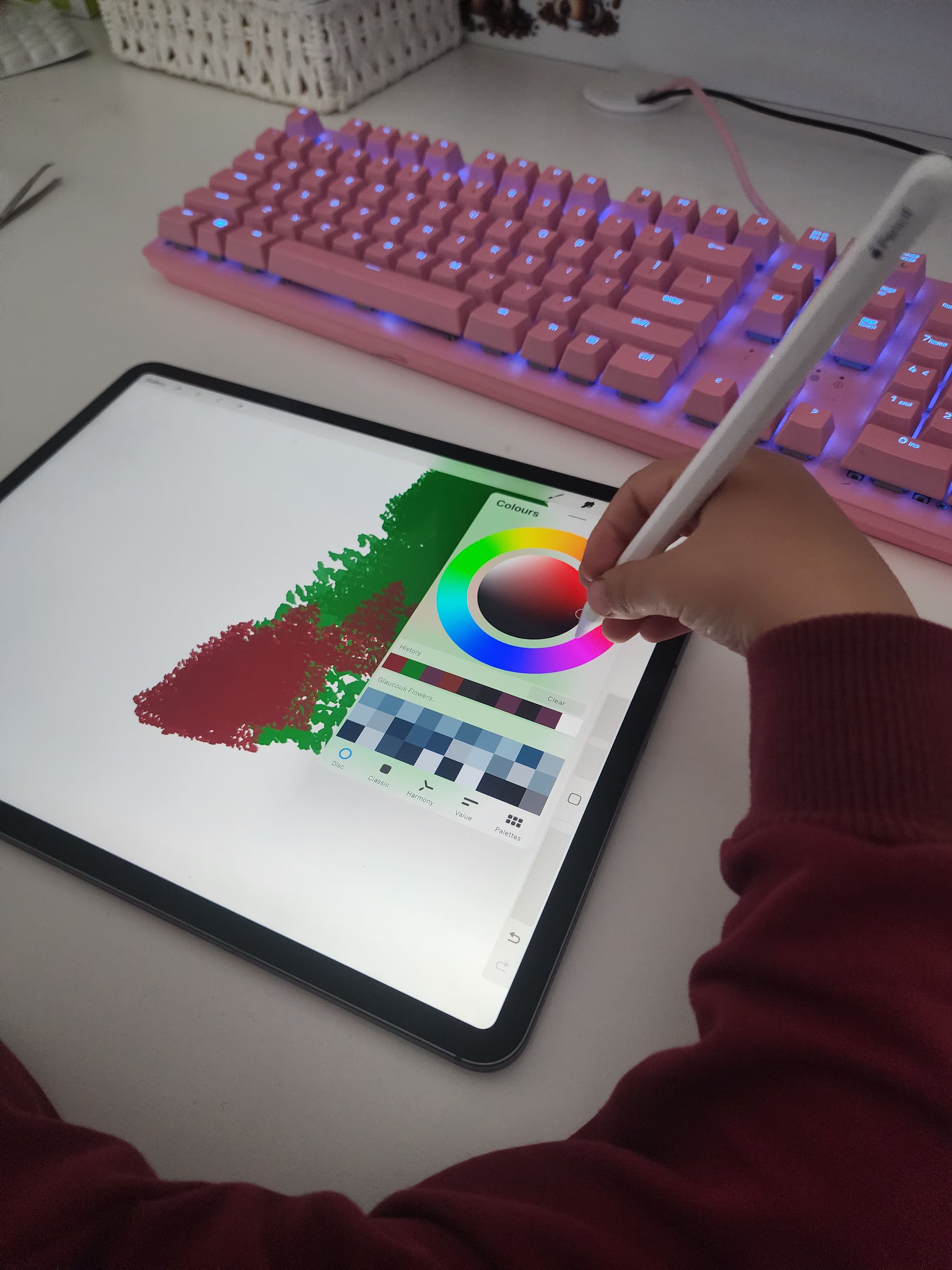 Person creating digital art on iPad using stylus, with pink mechanical keyboard in background