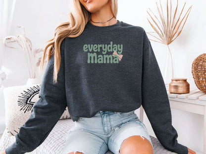 Model wearing dark grey Everyday Mama sweatshirt featuring green retro letters and a soft pink bow.