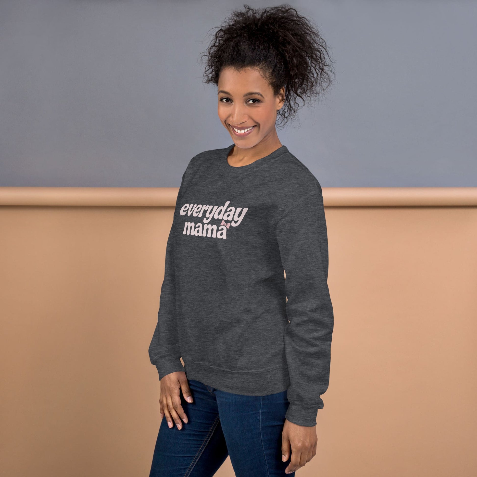 Woman wearing a gray sweatshirt with 'everyday mama' text against a neutral background