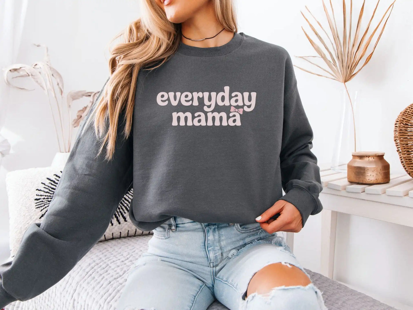 Model wearing dark grey Everyday Mama sweatshirt with pink bow graphic