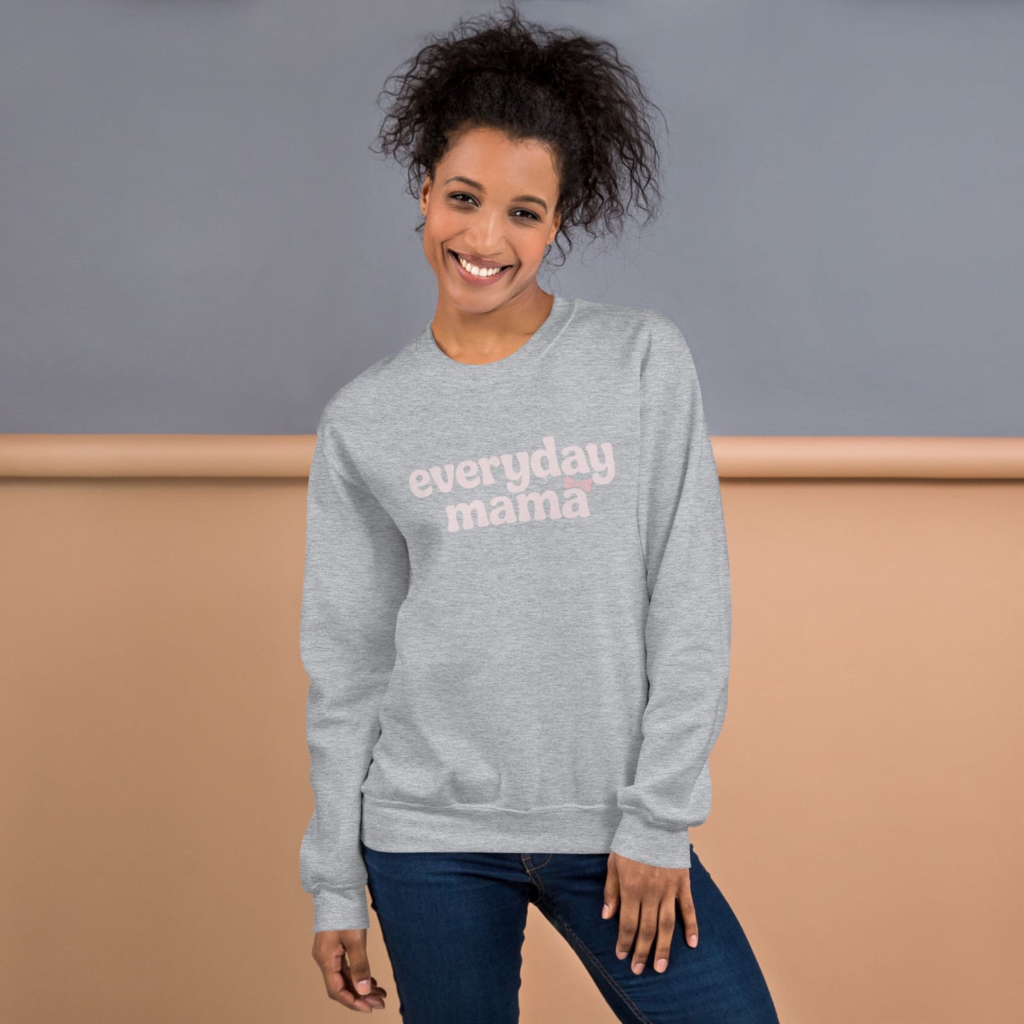 Woman wearing a gray sweatshirt with 'everyday mama' text against a neutral background