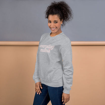 Woman wearing a gray sweatshirt with 'everyday mama' text against a plain background