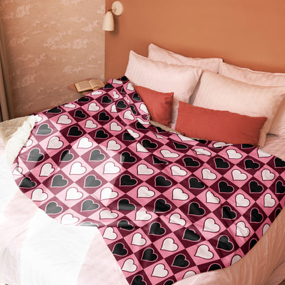 Full view of pink, white, and black heart throw blanket spread across bed