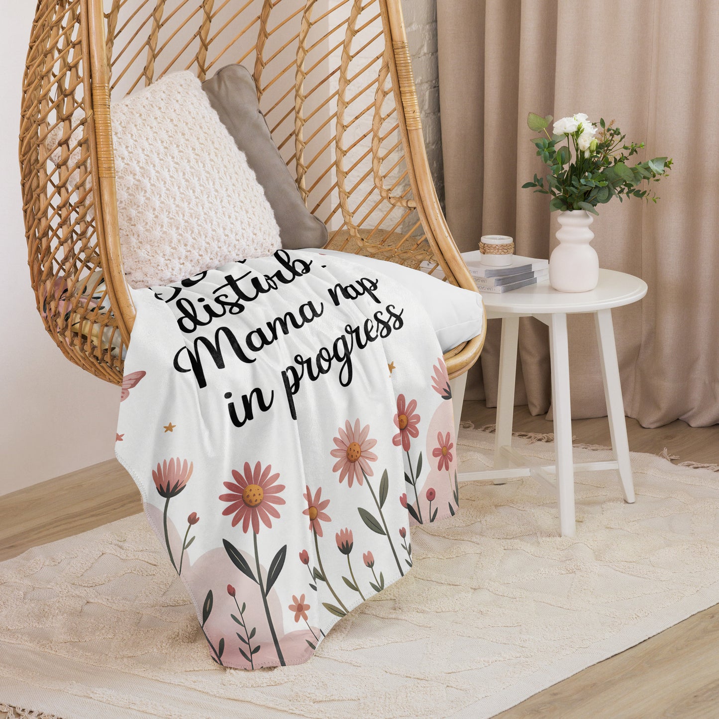 “Mama nap in progress” blanket draped over cozy hanging chair with floral pastel design.