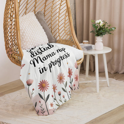 “Mama nap in progress” blanket draped over cozy hanging chair with floral pastel design.