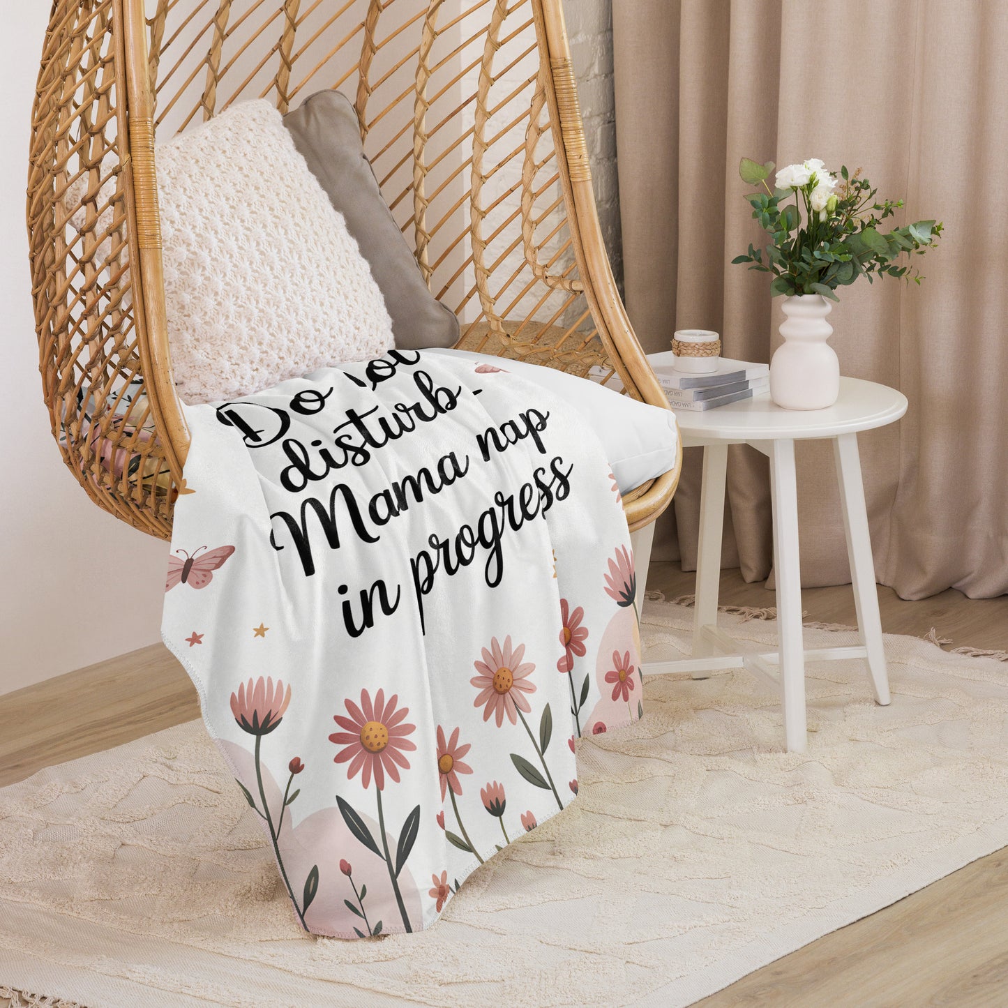 “Mama nap in progress” blanket draped over cozy hanging chair with floral pastel design.