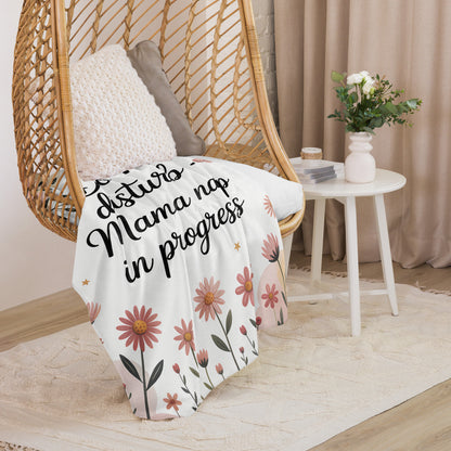 “Mama nap in progress” blanket draped over cozy hanging chair with floral pastel design.