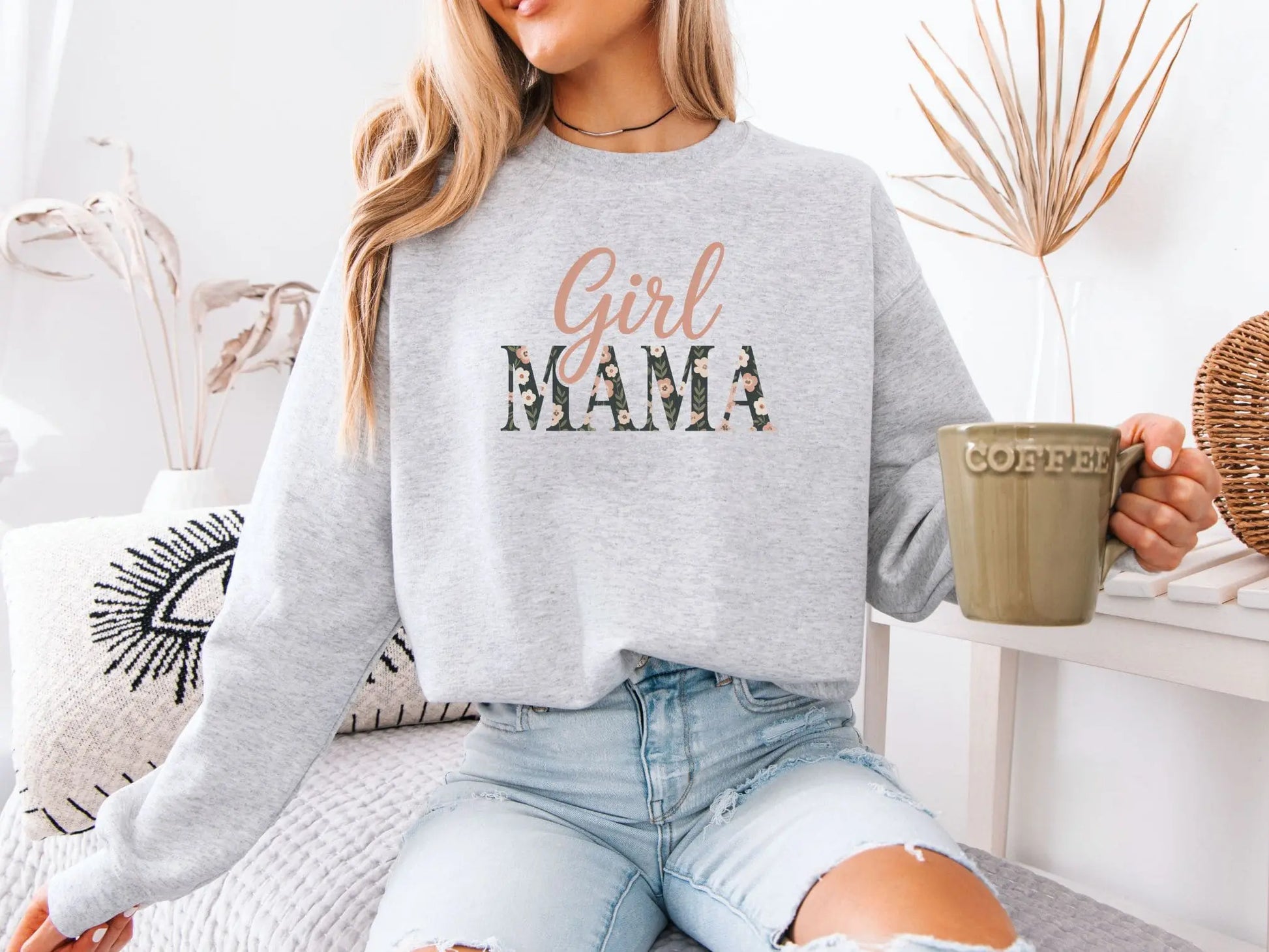 Person wearing a gray sweatshirt with 'Girl Mama' text, holding a coffee mug.