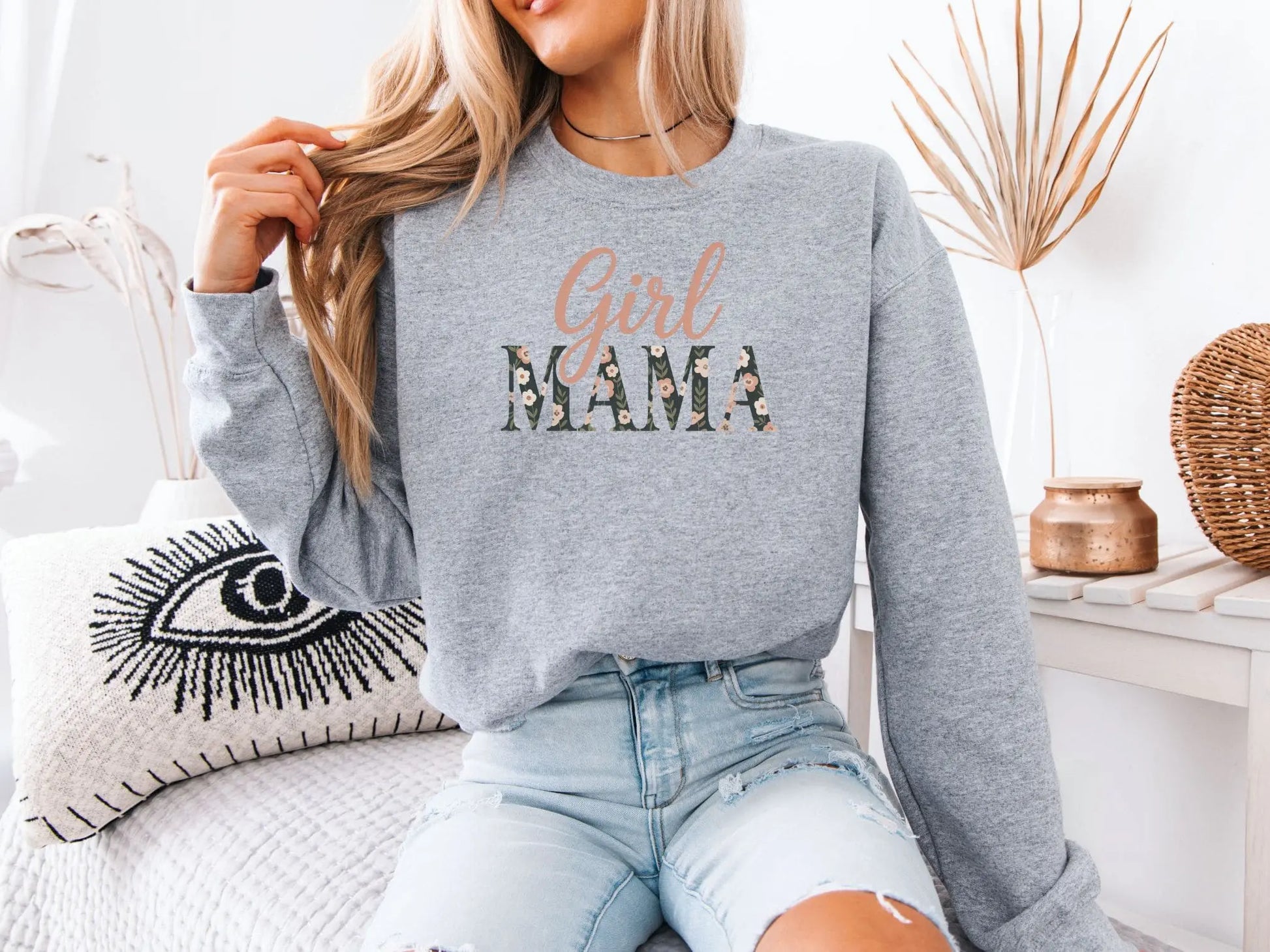 Person wearing a gray sweatshirt with 'Girl Mama' text in a home setting
