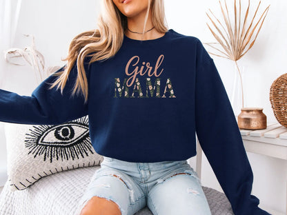Woman wearing a navy blue sweatshirt with 'Girl Mama' text, sitting on a couch.