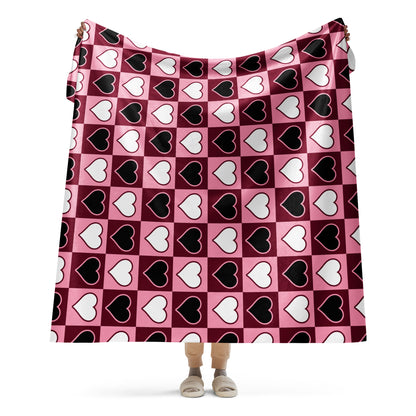 Full view of large heart pattern sherpa blanket held up by a person, showing the full design in pink, white, and black