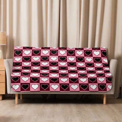 Medium-size pink sherpa blanket with cute heart design styled on a modern sofa