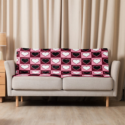 Small heart pattern sherpa blanket draped over a neutral beige sofa