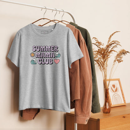 Heather grey t-shirt with pastel "Summer Mama Club" design hanging on a white rack with cozy boho decor in the background.