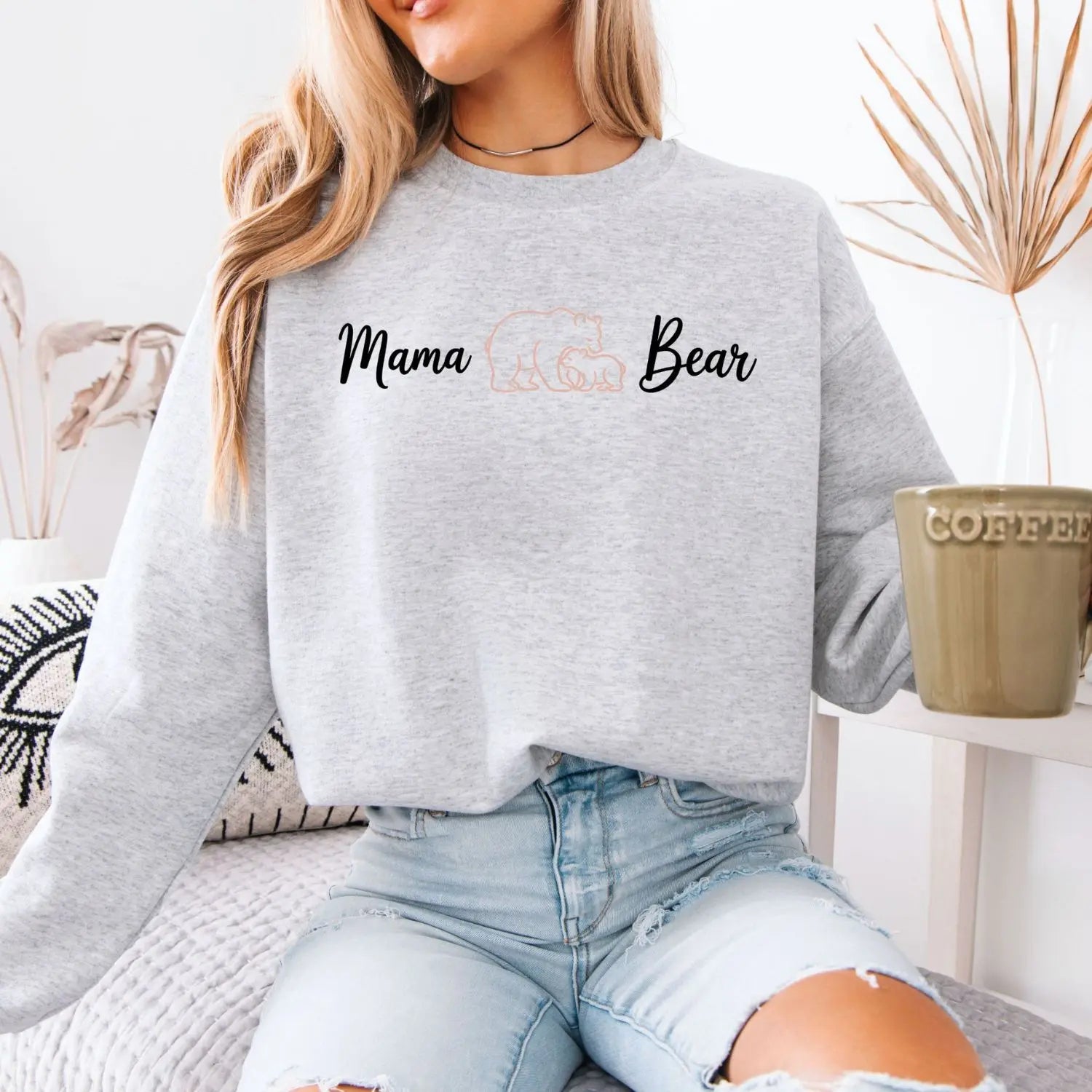 Person wearing a gray sweatshirt with 'Mama Bear' text, sitting indoors.