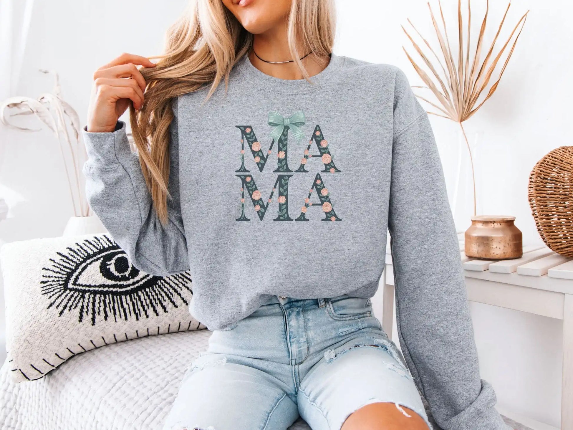 Person wearing a gray sweatshirt with 'MAMA' print, sitting on a couch.