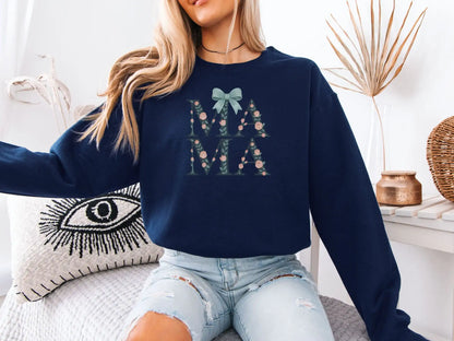 Person wearing a navy blue sweatshirt with 'MAMA' text and floral design, sitting on a couch.