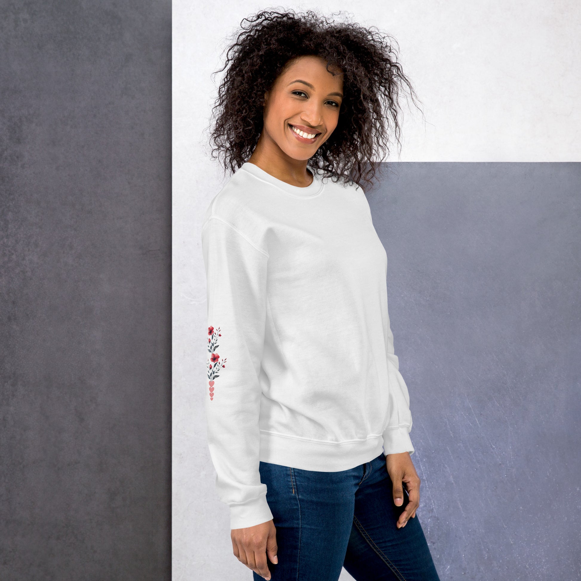 Smiling woman wearing white sweatshirt with floral design detail on the sleeve-right side
