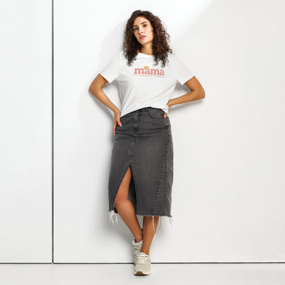 Woman wearing white ‘mama’ t-shirt with pastel sun design, styled with denim skirt, standing against white wall