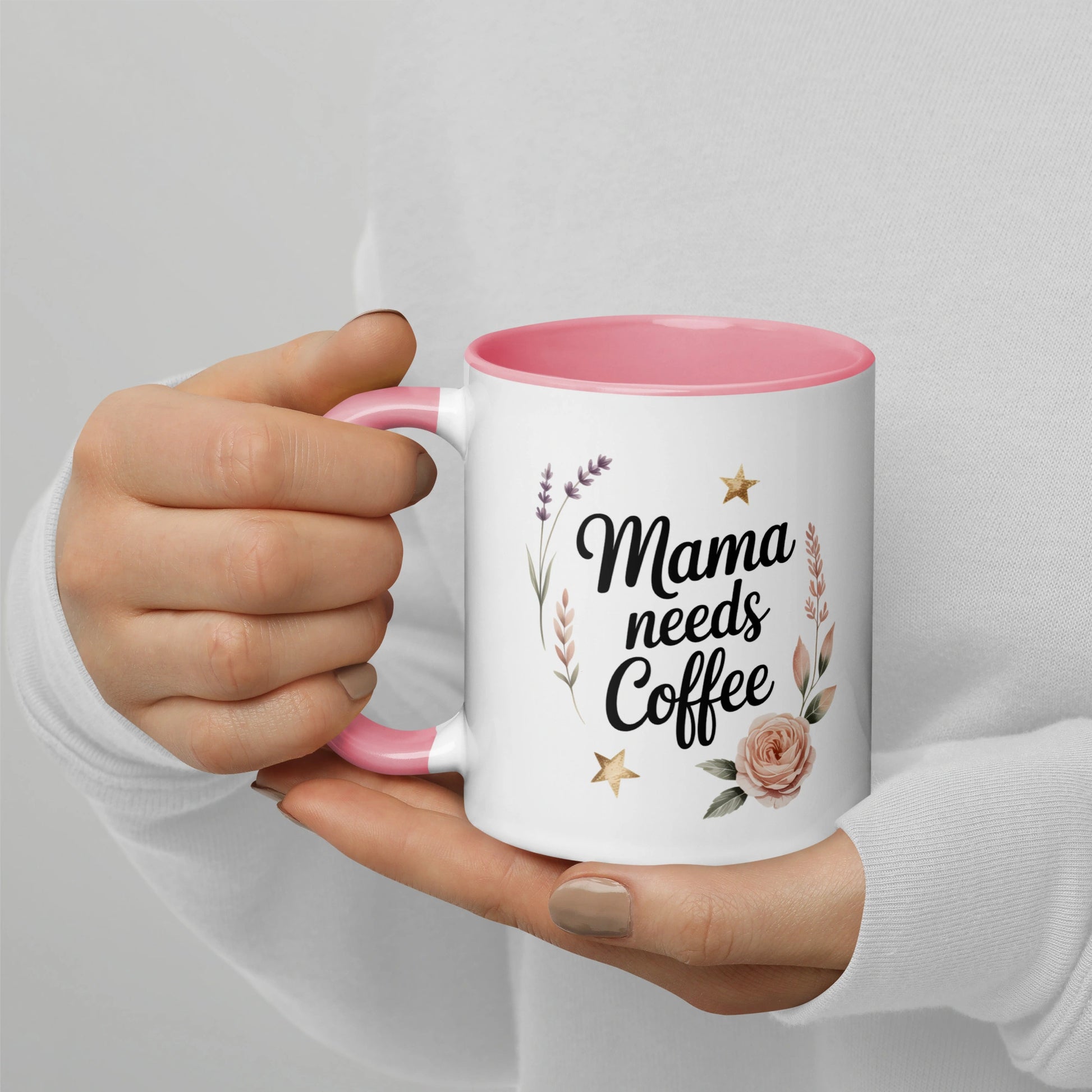 Close-up of “Mama Needs Coffee” ceramic mug held in hand, pastel stars and flowers.