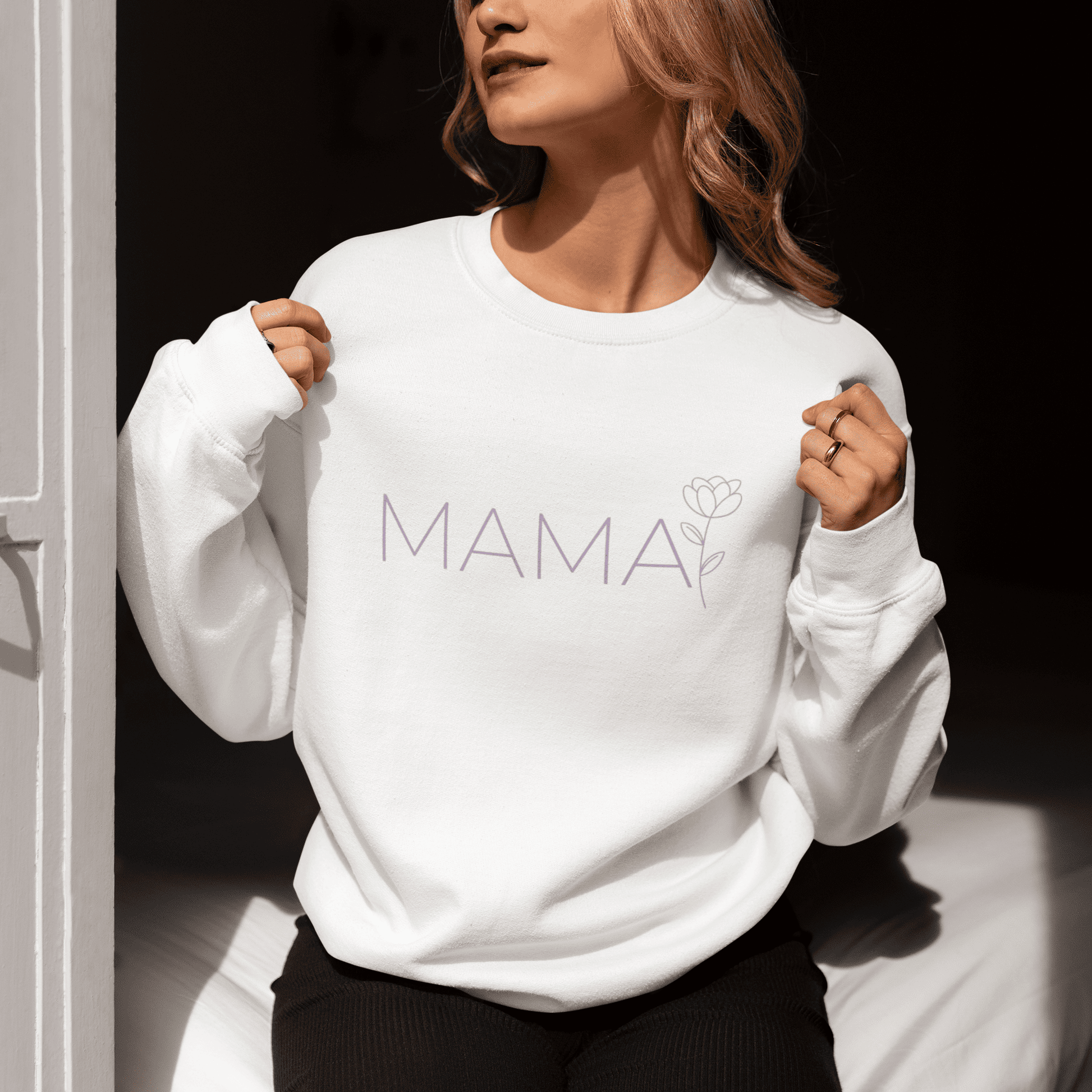 Woman wearing a white minimalist MAMA sweatshirt with floral design, sitting by the window and enjoying the sunlight

