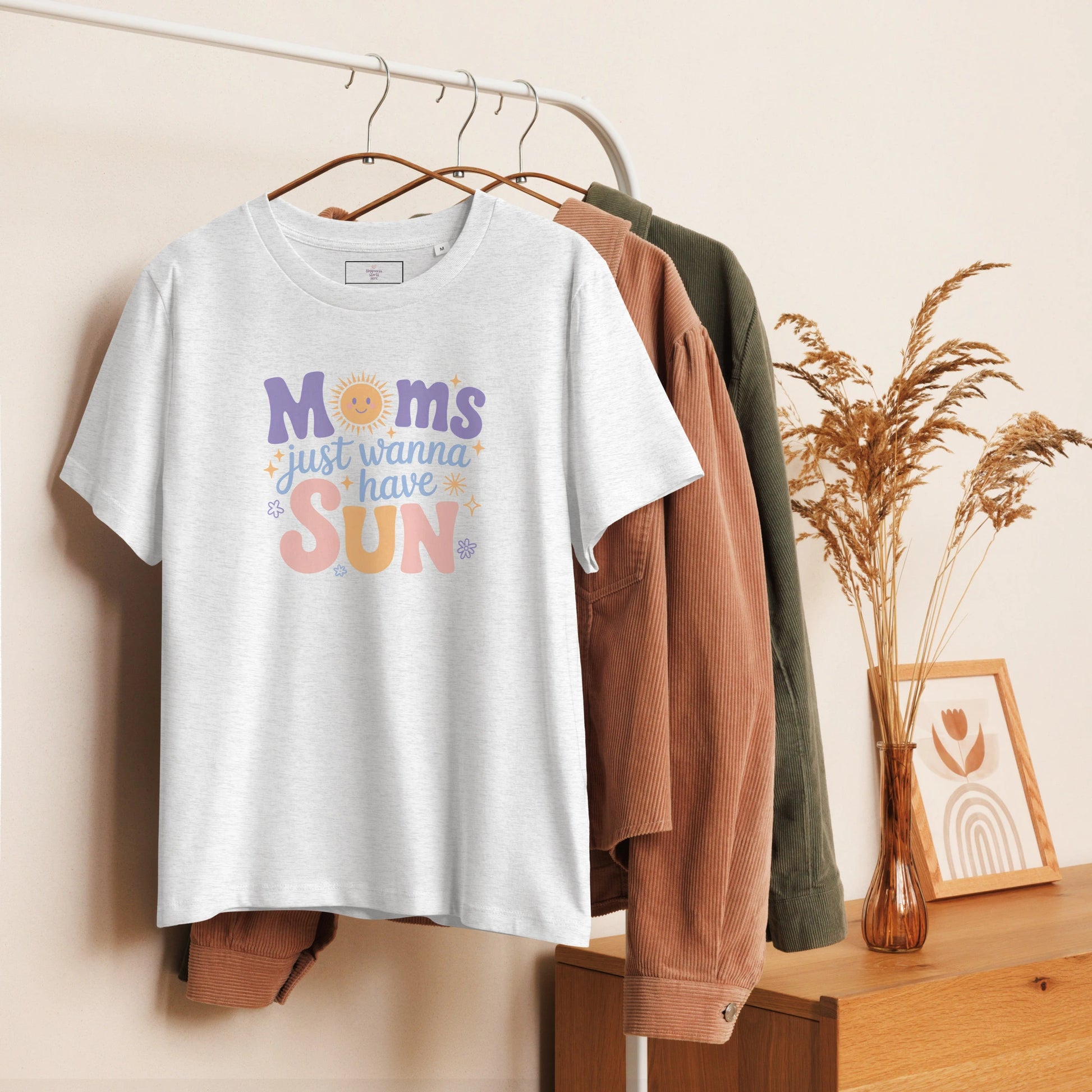 Heathered grey t-shirt with “Moms Just Wanna Have Sun” pastel design hanging on clothing rack – cozy styled product photo for summer t-shirt for moms