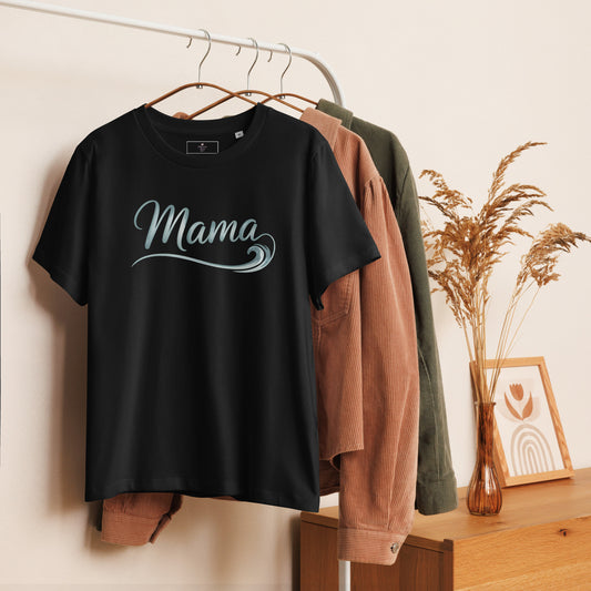 Black Ocean Mama t-shirt with wave lettering hanging on clothing rack, styled with cozy summer tones.