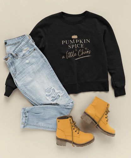Black sweatshirt with text "Pumpkin spice & a little chaos", light blue jeans, and yellow boots on a beige background