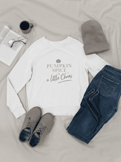 White sweatshirt with 'Pumpkin Spice & a Little Chaos' text, paired with jeans, shoes, and a beanie on a light surface.