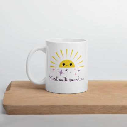 White ceramic mug with a cute yellow sun and pastel sparkles, featuring the phrase "Start with sunshine" — cozy gift for moms and coffee lovers.